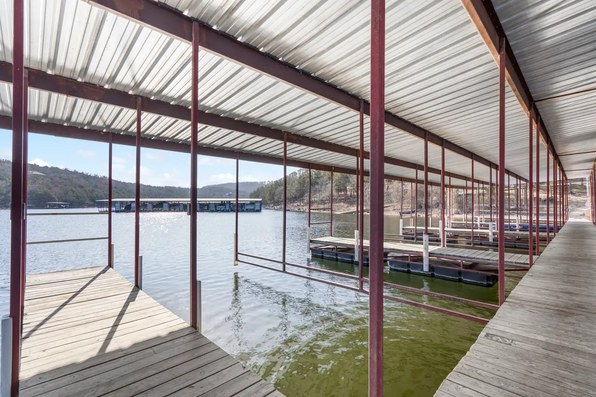 The image showcases serene boathouses and a dock structure set along a calm water surface, perfectly illustrating the atmosphere of lakeside leisure. The peaceful mood, early morning light, and reflections on the water evoke the experience of fishing trips, prepping for boating, or unwinding after watersports.