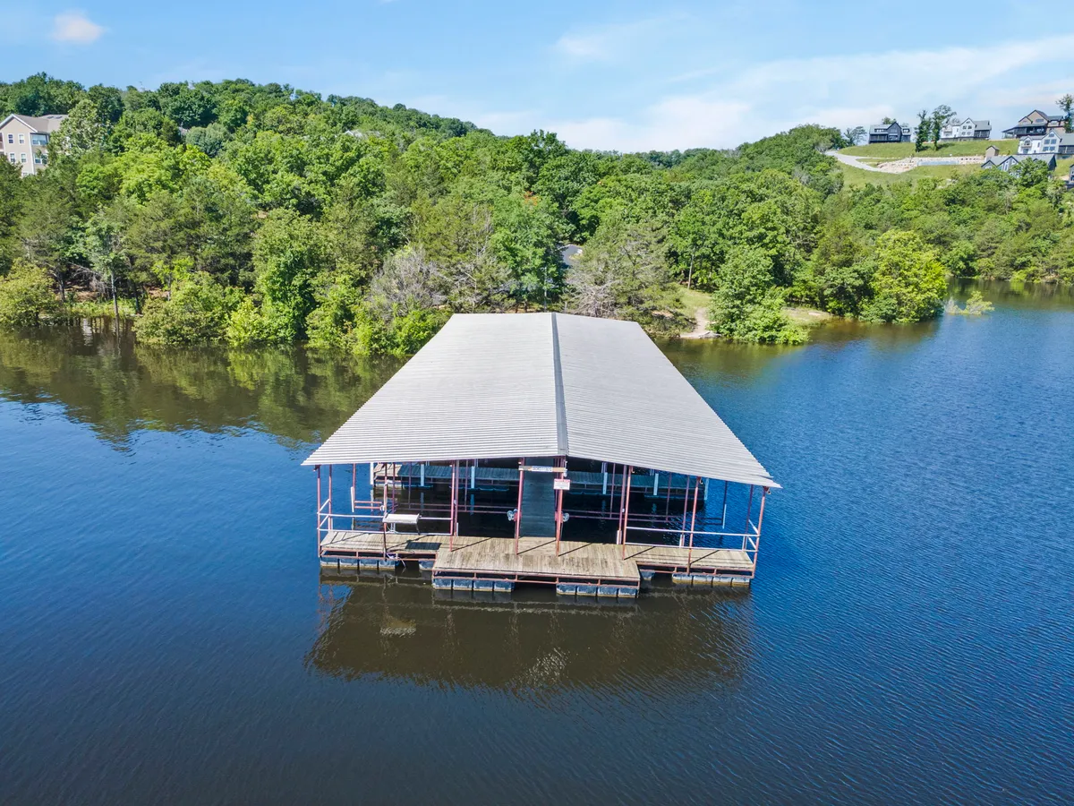 A floating dock gently extending over calm, clear water, surrounded by lush greenery. The dock offers direct access for boating, fishing, and peaceful moments by the lake—ideal for launching a boat or simply enjoying the lake views.