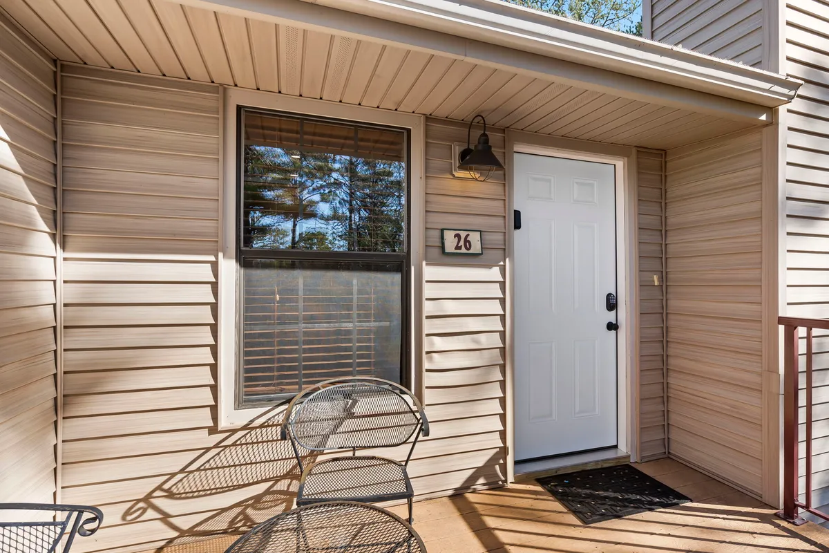 An inviting view of the bungalow's front porch, with a pair of chairs positioned to enjoy the outdoors. The scene highlights a cozy, private spot perfect for sharing morning coffee or evening chats, framed by greenery and the welcoming entrance.