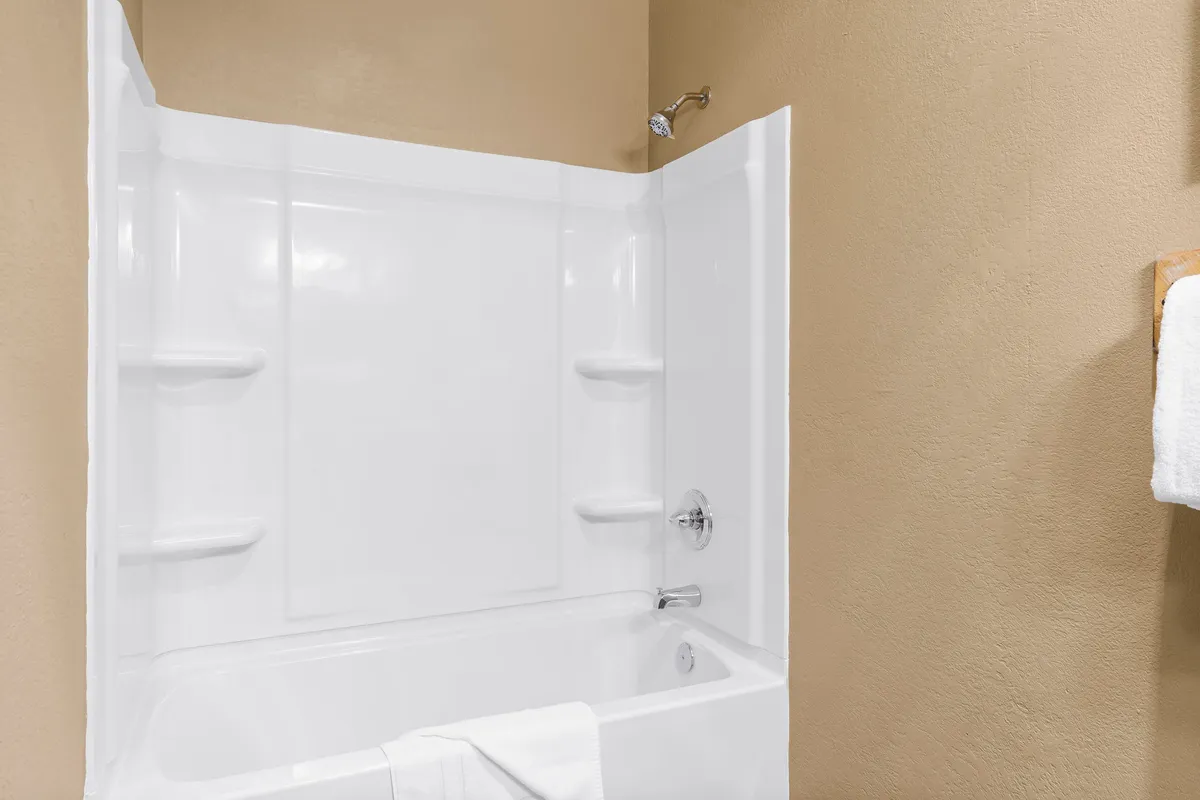 A spa-like ensuite bathroom with a bathtub, modern showerhead, towel rack, and fluffy towels. The space feels clean, bright, and relaxing, inviting guests to refresh and rejuvenate after a day of activities.
