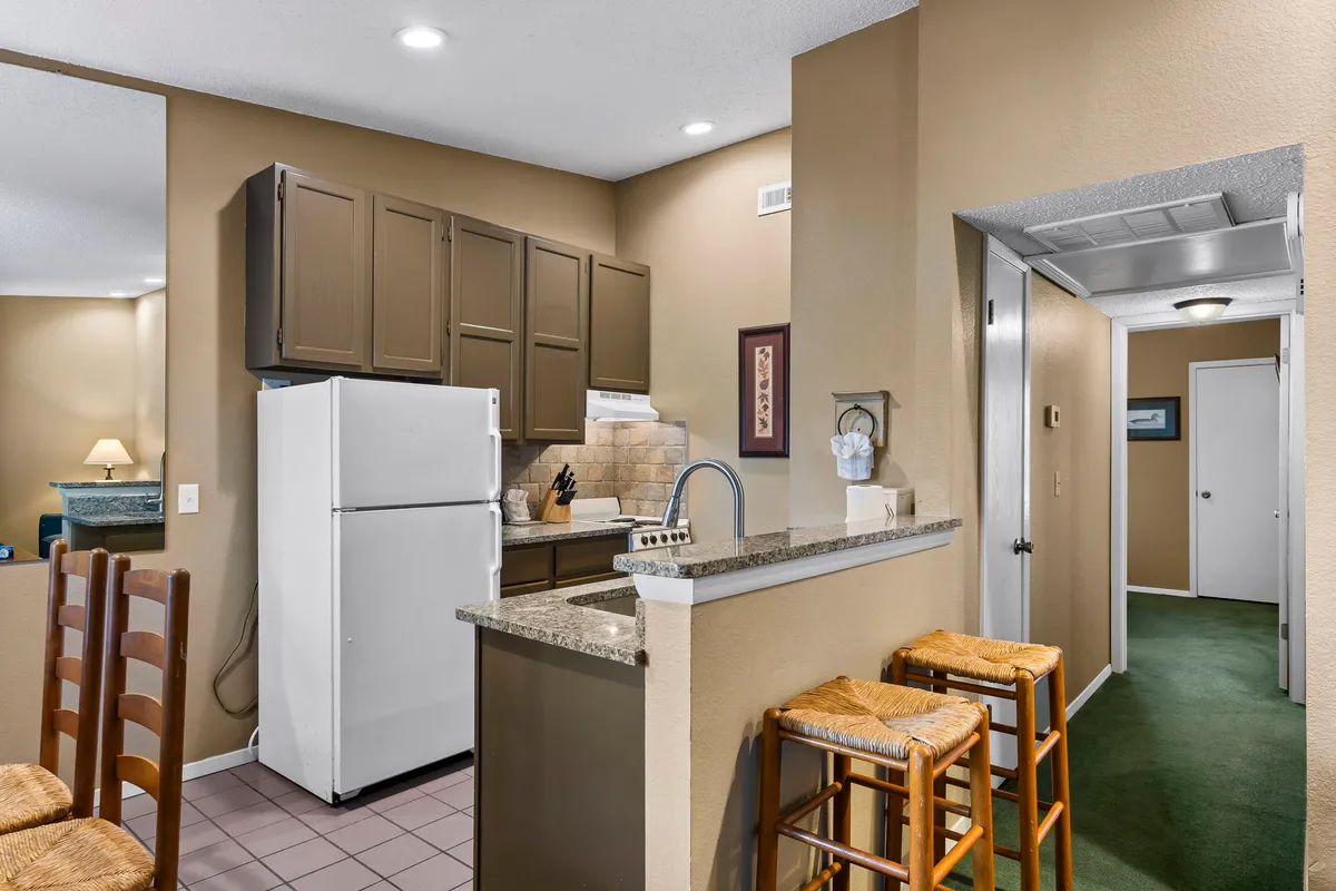A welcoming kitchen featuring a large kitchen island with bar stools, modern refrigerator, and elegant cabinetry. The space is designed for both cooking and casual dining, with ample counter space for meal prep and gatherings.