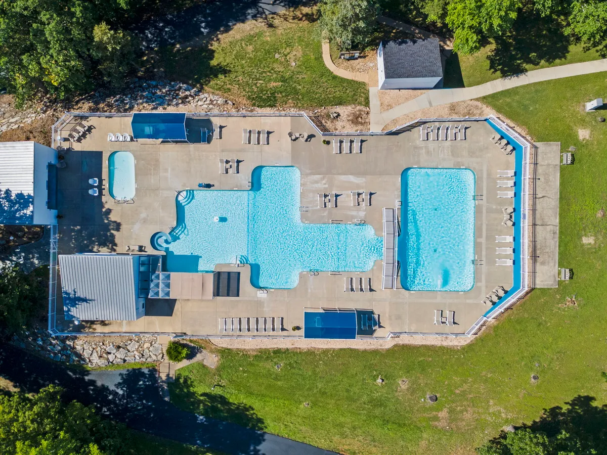 A sparkling outdoor swimming pool with lounge chairs nestled among trees and greenery. The space is designed for leisure and relaxation, with enough room for families to splash, swim, and unwind together under the sun.