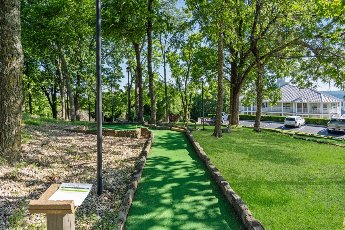 A playful mini-golf course tucked among trees, featuring colorful signage and inviting green fairways. The area is designed for family fun, friendly competitions, and making vacation memories together amidst nature.